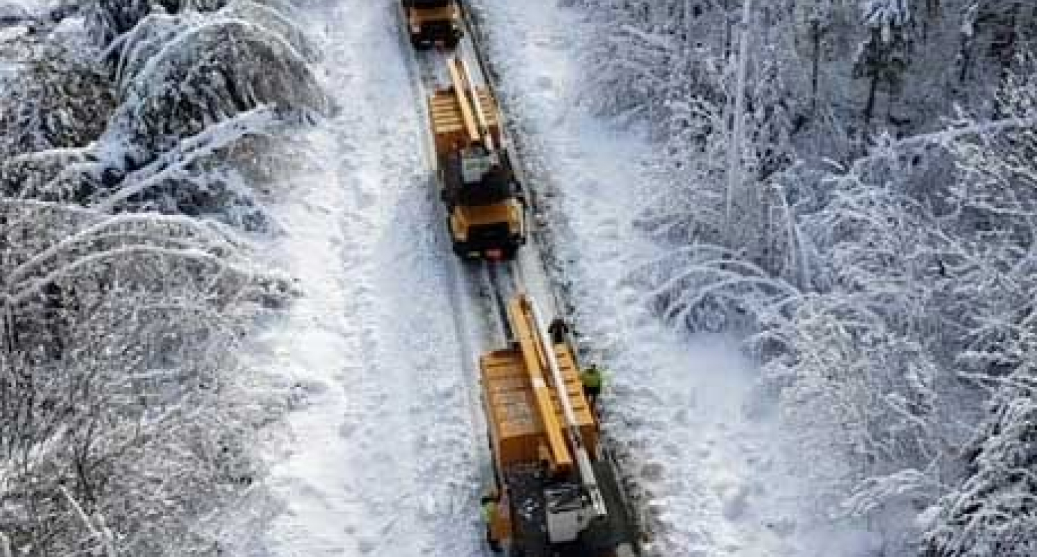 Overhead view of several NG Gilbert trucks driving through a wintery landscape.