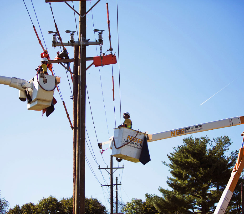 Two NG Gilbert team members in cherry pickers work on a power line.