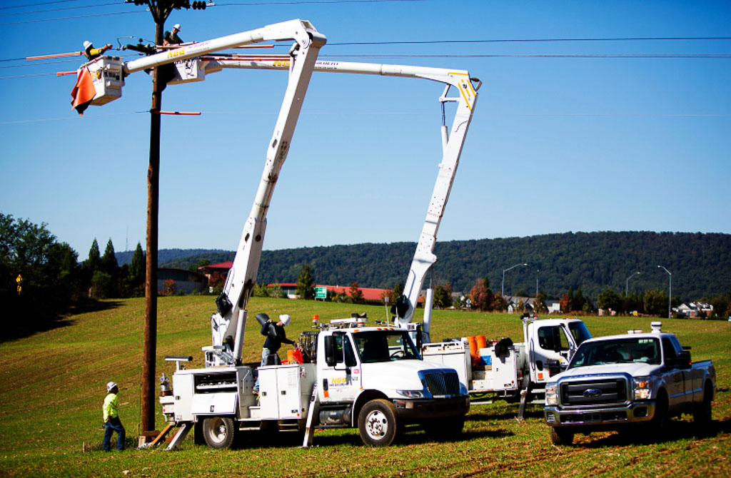 NG Gilbert team members work on a power line using trucks with cherry pickers.