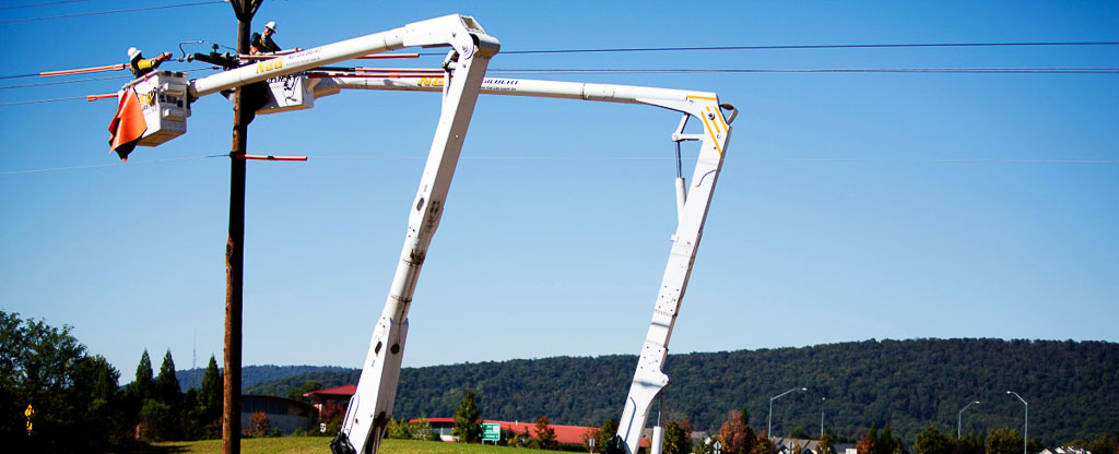 Two NG Gilbert cherry picker trucks holds several crew members as they lift two workers to work on an overhead line.