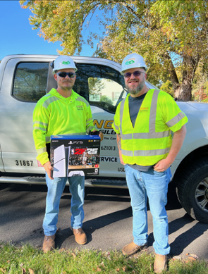 Two men standing in front of a truck, with one man holding a box.